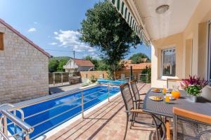 a patio with a table and chairs next to a swimming pool at Dalmatian village charm - spacious villa with pool near Trogir in Primorski Dolac