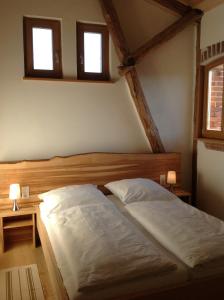 a bed in a bedroom with two windows at Gästehaus Landgut Lischow in Neuburg-Steinhausen
