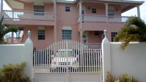 a white gate in front of a pink house at Sunset Bliss Villa in Anse La Raye