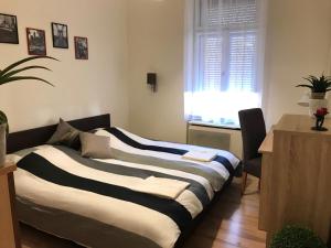 1 dormitorio con 2 camas, ventana y escritorio en City Apartman, en Pécs