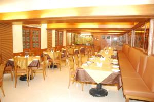 a dining room with tables and chairs in a restaurant at Hotel Nahar Manchester Inn in Coimbatore