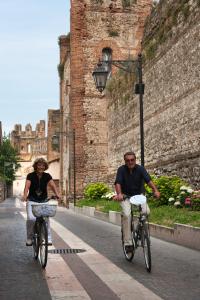 Un uomo e una donna in bicicletta lungo la strada di Cangrande Hotel a Lazise