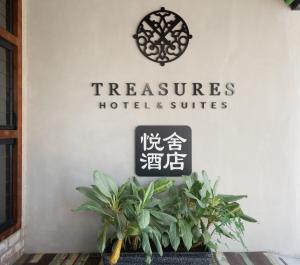 um sinal que lê tesouros hotel e suites em uma parede com plantas em Treasures Hotel and Suites em Malaca