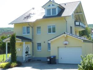 een groot geel huis met een witte garage bij Ferienwohnung Schneckental in Pfaffenweiler