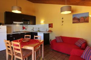 a living room with a table and a red couch at Gite Guillot - hameau calme 8km de Jonzac in Nieul-le-Virouil