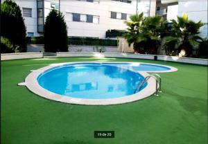 a large swimming pool in the middle of a green lawn at Cálido apartamento con piscina en Barcelona in Ripollet