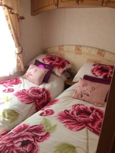 two beds in a room with flowers on them at Dolafon Farm Stay in St Asaph