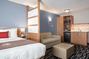 a hotel room with a bed and a chair and a kitchen at Microtel Inn & Suites by Wyndham Val-d Or in Val-dʼOr
