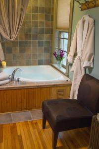 Pinehurst Inn Bed & Breakfast في بايفيلد: حمام مع حوض استحمام وكرسي