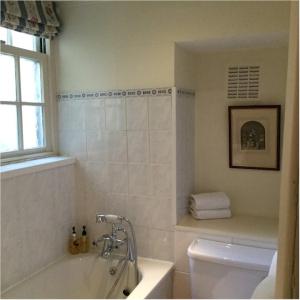 a bathroom with a tub and a toilet and a window at Bath Place Hotel in Oxford