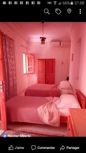 two beds in a bedroom with pink walls at Residence Tozeur Almadina in Tozeur