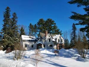 una casa vieja en la nieve con árboles en Pinehurst Inn Bed & Breakfast, en Bayfield