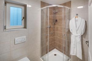 uma casa de banho com um chuveiro e um roupão branco em Louren Apartments em Praga