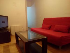 マドリードにあるApartamentos pandiellos Iのリビングルーム(赤いソファ、ガラステーブル付)