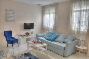 a living room with a blue couch and a tv at SEVILLA BUTTERFLY SUITES in Seville