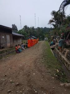 a group of people sitting on the side of a dirt road at Lattanavongsa guesthouse and Bungalows in Muang Ngoy