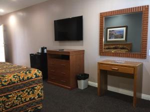 a hotel room with a bed and a desk and a television at Dunes Inn - Wilshire in Los Angeles