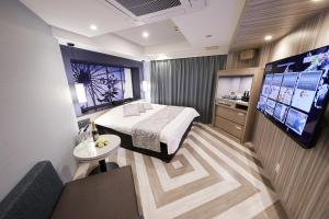 a hotel room with a bed and a flat screen tv at Hotel Sen (Adult Only) in Osaka