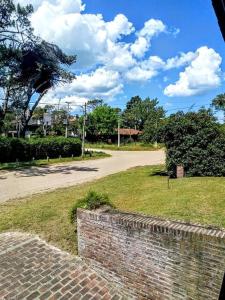 una pared de ladrillo junto a una calle y una carretera en Tejas Verdes Alojamiento Familiar, en Villa Gesell