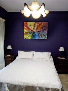 Un dormitorio con una cama blanca y un cuadro en la pared. en Tejas Verdes Alojamiento Familiar, en Villa Gesell 13 fotos más