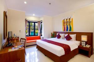 a bedroom with a bed and a desk and a television at Restu Bali Hotel in Legian