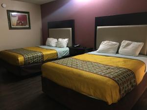 a hotel room with two beds with yellow sheets at Express Inn in Lafayette