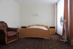 a bedroom with a bed and a chair and a fan at Gostinitsa Ust'-Ilim in Ust'-Ilimsk