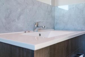 lavabo blanco en el baño con espejo en Sunset Motel, en Thames