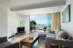 ein Wohnzimmer mit einem Sofa, einem TV und einem Tisch in der Unterkunft at Marina Shores in Airlie Beach