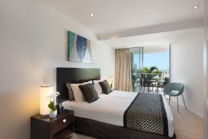 a hotel room with a bed, chair, and nightstand at at Marina Shores in Airlie Beach