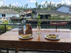 a wooden table with two plates of food on it at Baan Rabieng Talay Homestayบ้านระเบียงทะเล โฮมสเตย์เกาะกูด in Ko Kood