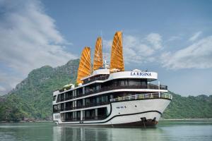 a cruise ship in the water with mountains in the background at La Regina Legend Cruise in Ha Long