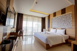 a hotel room with a large bed and a desk at Aqua Resort SHA Plus in Rawai Beach