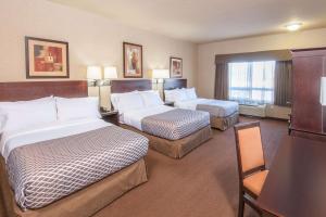 a hotel room with two beds and a television at Ramada by Wyndham Drumheller Hotel & Suites in Drumheller