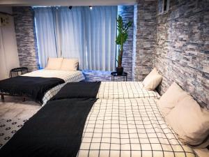 two beds in a room with a brick wall at Yoyogi Apartment 2-301 in Tokyo