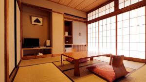 - un salon avec une table, des chaises et des fenêtres dans l'établissement Wakaki Ryokan - Nasu Yumoto Onsen, à Nasu