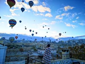 a person is looking up at a bunch of hot air balloons at Cappadocia Elite Stone House in Goreme