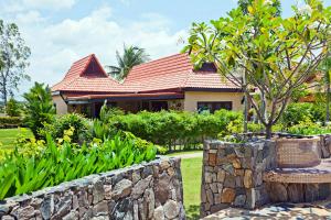 a house with a stone wall and a tree at Family-friendly house, a few steps from the pool and close to the ocean. in Mae Pim