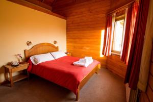 um quarto com uma cama com um cobertor vermelho e uma janela em Linda Vista Apart Hotel em El Calafate