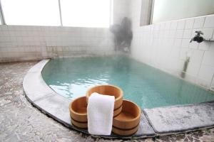 - Baño con piscina de agua y toalla en Yamadaya Ryokan, en Nozawa Onsen