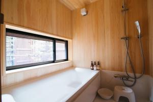 a bathroom with a tub and a window and a shower at Ryu TABI-NE in Kanazawa