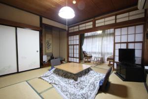 a living room with a table and a tv at Yamadaya Ryokan in Nozawa Onsen