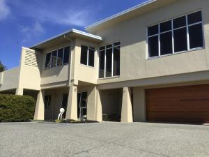 a large white house with a garage at Treetops On Heta in New Plymouth