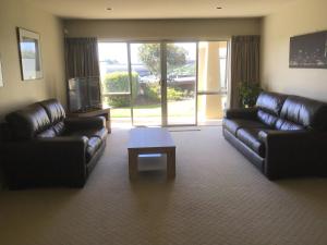 a living room with two leather couches and a coffee table at Treetops On Heta in New Plymouth