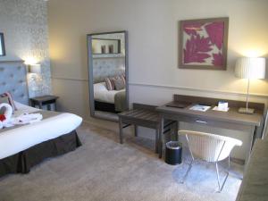 a bedroom with a bed and a desk and a mirror at Hôtel Le Royal Promenade des Anglais in Nice