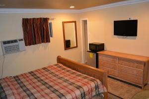 a bedroom with a bed and a dresser and a television at Bayshore Inn Ventura in Ventura