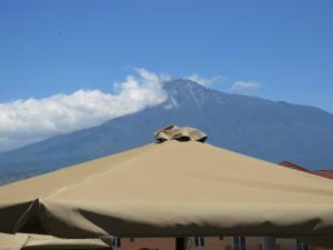 a large tan umbrella with a mountain in the background at Boulevard Inn Mt Meru in Arusha