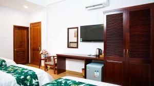 Habitación de hotel con escritorio y TV en Flora Quy Nhon Hotel, en Quy Nhon