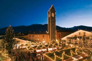 um mercado de Natal numa cidade com uma torre de relógio em Appartamentino Frundsberg em Vipiteno