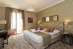 a hotel room with a large bed and a desk at Hôtel Le Royal Promenade des Anglais in Nice